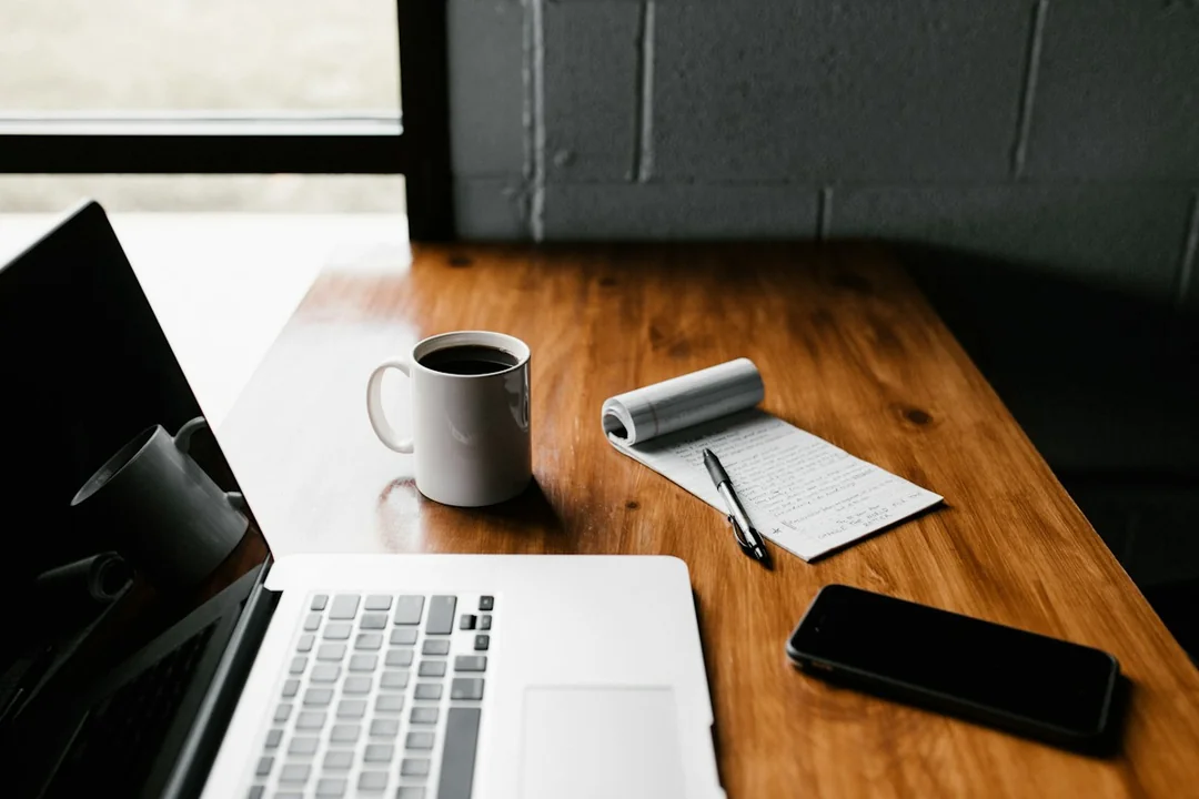 A laptop, notebook and coffee on a desk