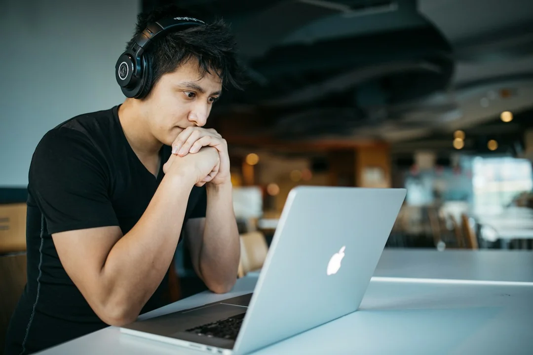 A person wearing headphones while studying with a laptop